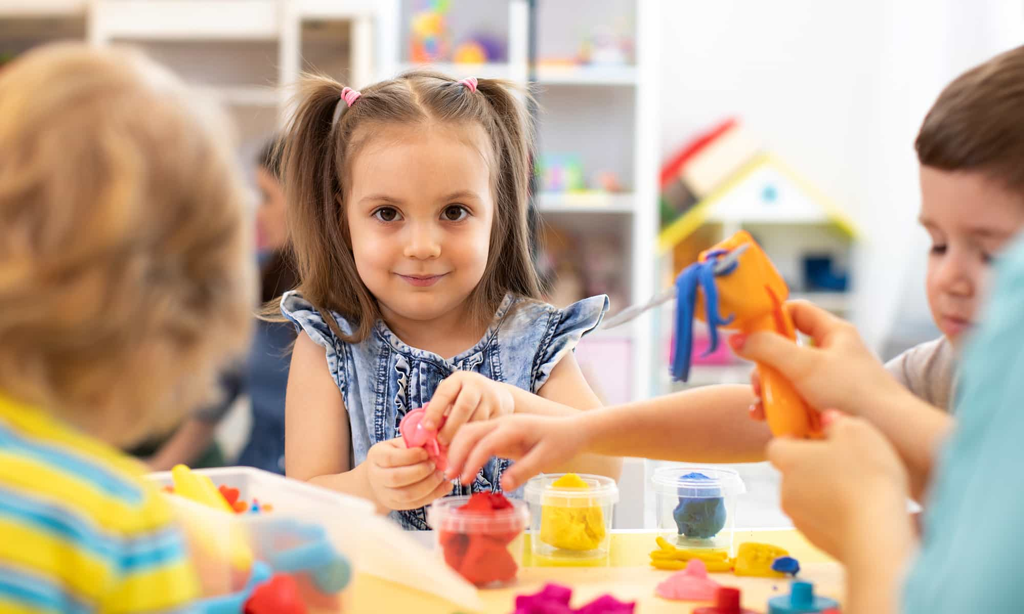 Girl playing with coloured clay at table